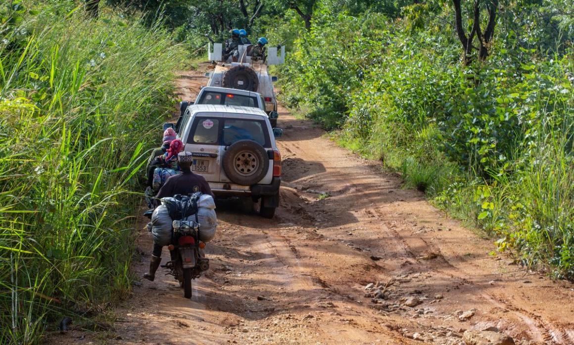 Vehicles are motorbikes cross a dirt path.